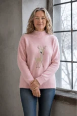 Colette pink embroidered half-collar knit sweater, model standing by a window with hands gently crossed.
