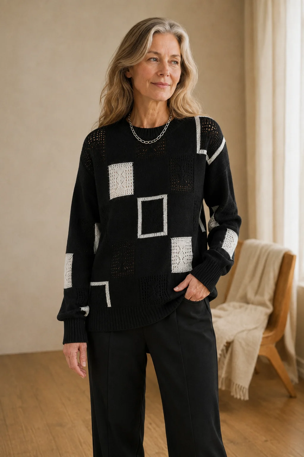Grace black geometric knit sweater with white square motifs, worn by the main product model with one hand in her trouser pocket