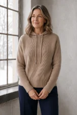 Graziella khaki rib-knit drawstring hoodie on the main product model with hands loosely clasped beside a window