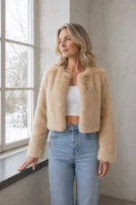 Idola apricot cropped faux-fur jacket, main product model resting one hand naturally on a windowsill